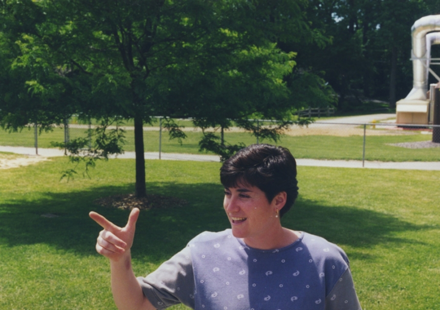 Coach Karen Borbee has short brown hair and is pointing while standing outside. 